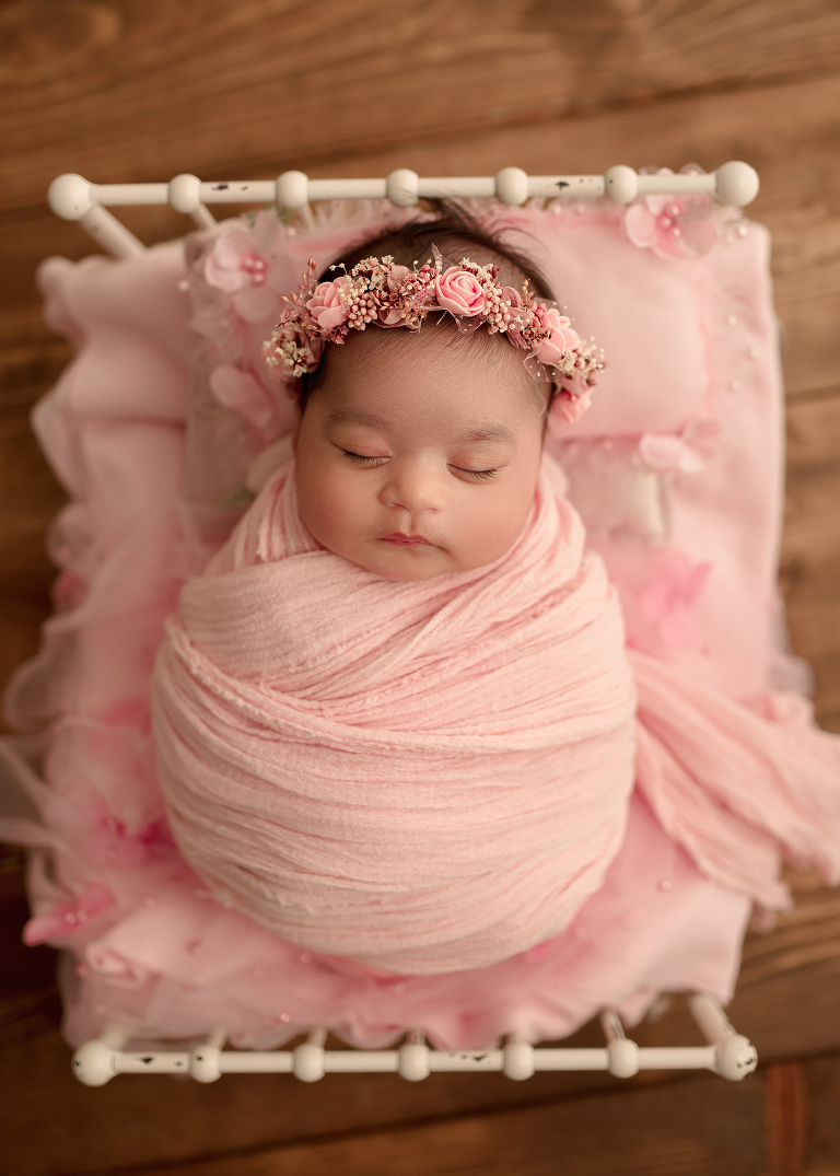 Baby girl lying on soft pink blanket, curled up naturally