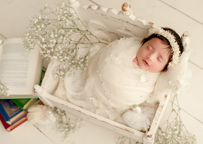 Newborn baby girl wrapped in soft cream blanket during photoshoot by Allen newborn photographer in Frisco studio