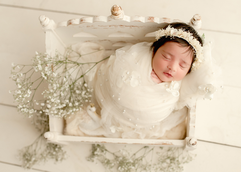Newborn baby girl wrapped in soft cream blanket during photoshoot by Allen newborn photographer in Frisco studio
