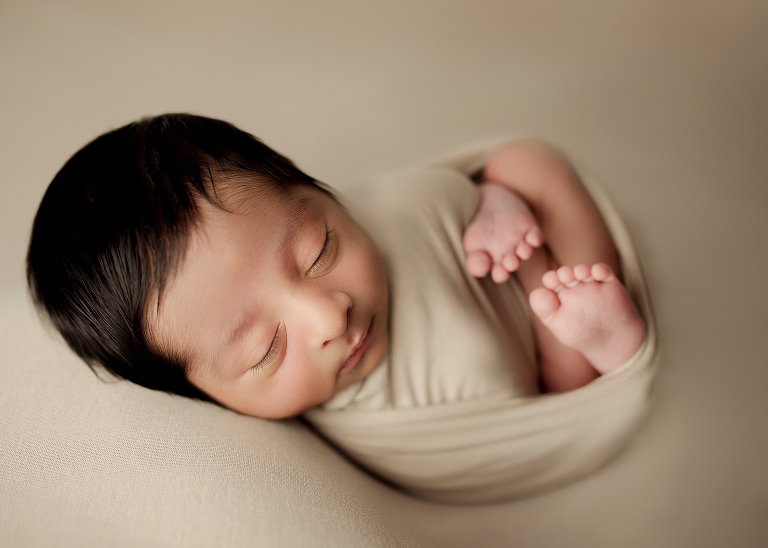 Professional Plano newborn photographer capturing baby boy portraits in blue, white, and brown tones