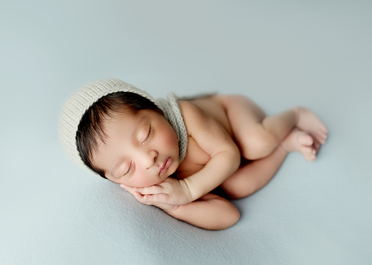 Professional Plano newborn photographer capturing baby boy portraits in blue, white, and brown tones